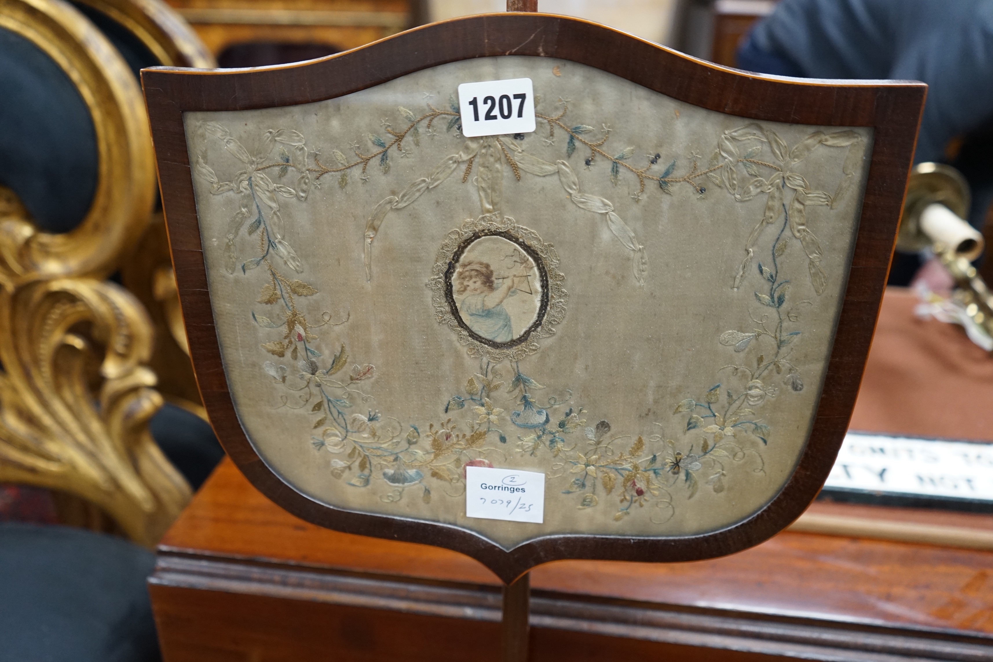 Two early 19th century shield shaped mahogany pole screens with silk embroidered banners, larger height 150cm